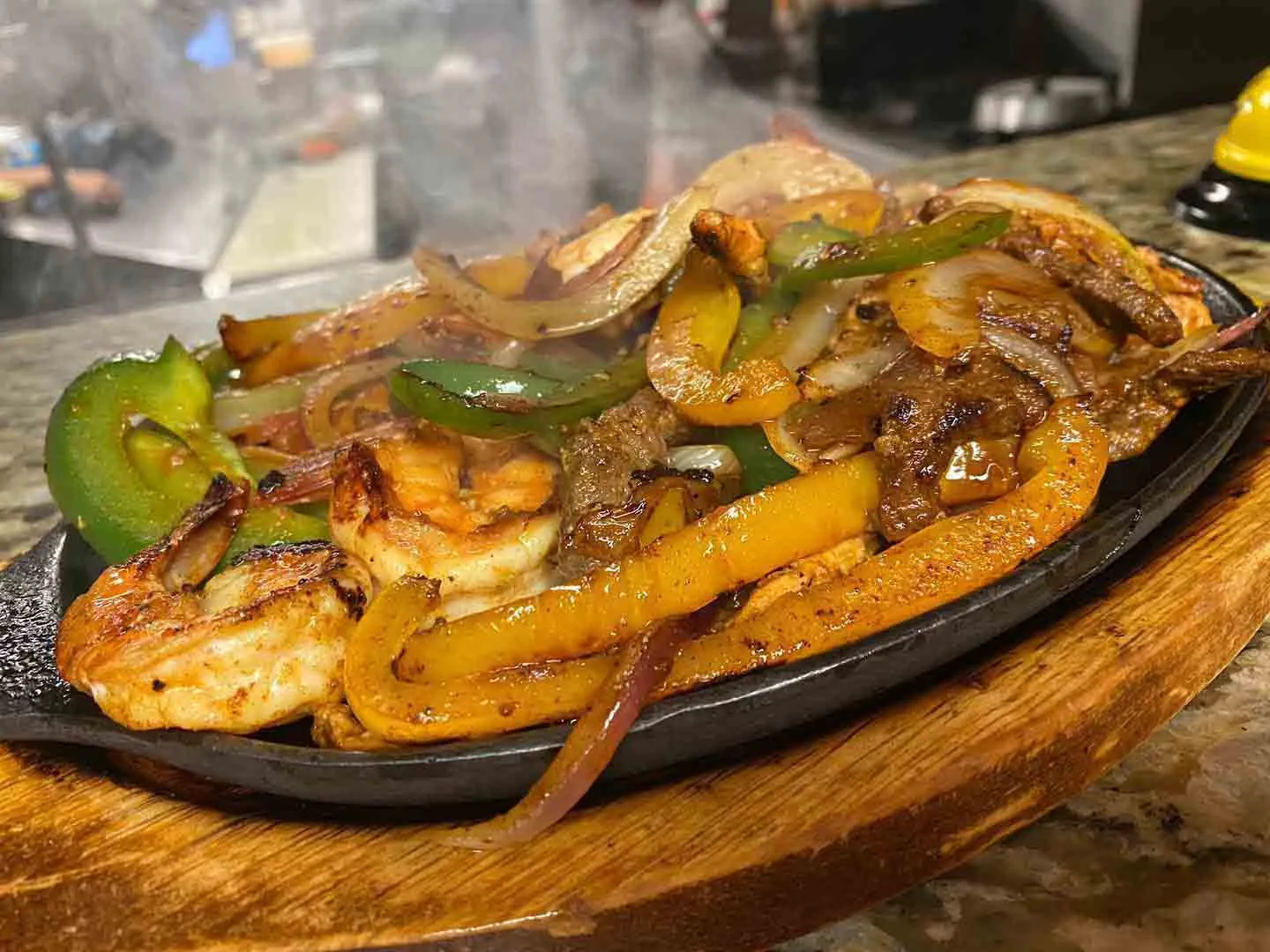 Sizzling fajitas with peppers and onions on a cast-iron platter